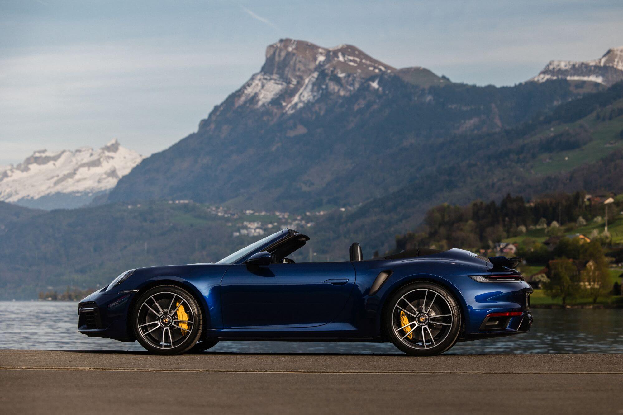 Luxury Porsche car parked in the Swiss Alps with breathtaking mountain scenery in the background