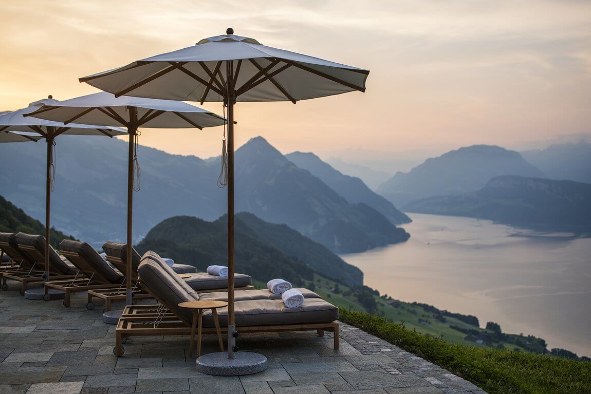 Luxury terrace at Villa Honegg with lounge chairs overlooking Lake Lucerne and the Swiss Alps