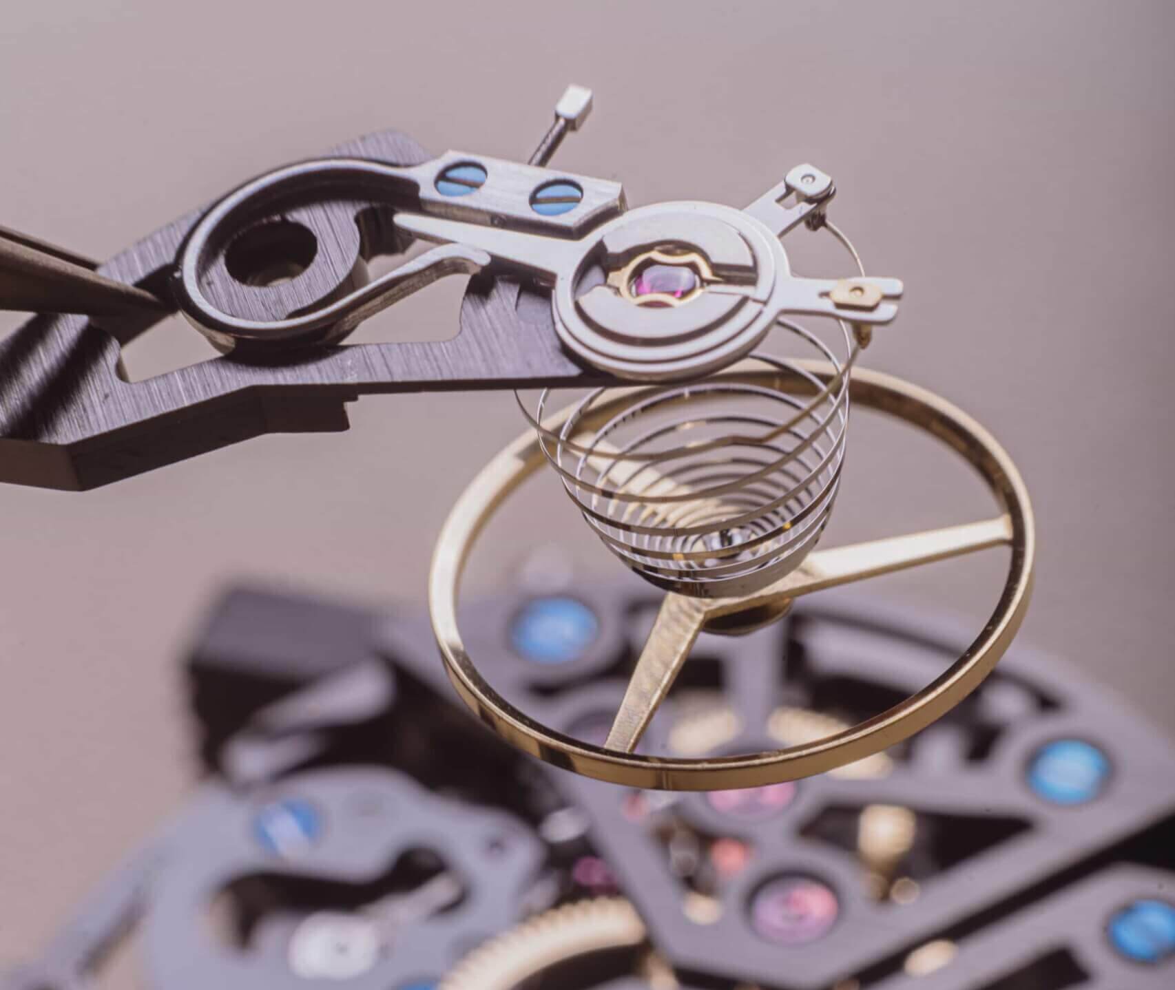 Close-up of a Swiss watchmaker using a precision tool to place a component on a luxury mechanical watch movement